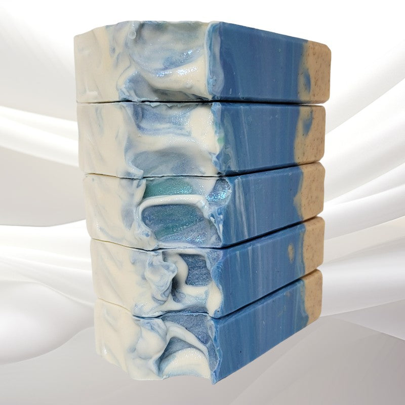 Five stacked bars of ocean-themed soap on a white sheer material