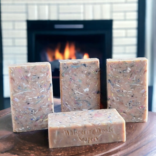 Four pinkish bars of soap with different colors of soap confetti throughout, with a fireplace in the background