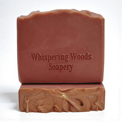 Two dusky rose colored bars of soap with 'Whispering Woods Soapery' branding