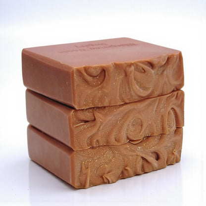 Three stacked soap bars with a decorative swirl pattern on top on a white background
