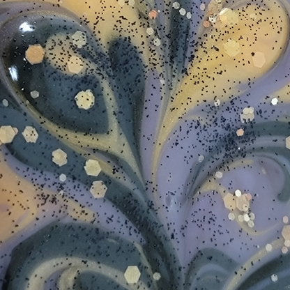 Extreme close-up of freshly poured gold, purple and black swirled soap with gold and black glitter on top