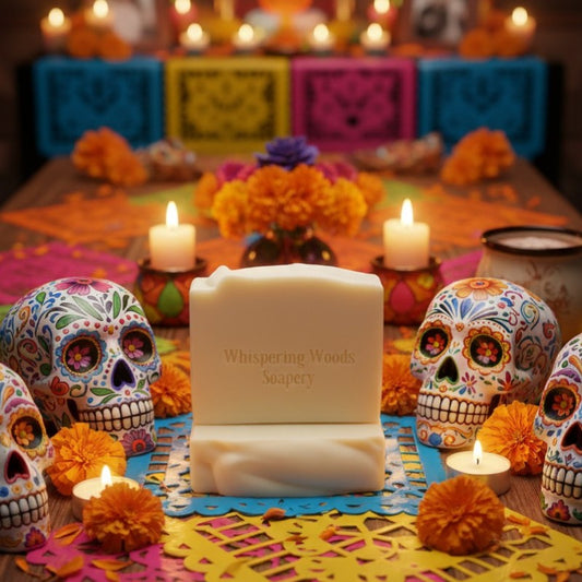 Two cream-colored bars of soap with 'Whispering Woods Soapery' branding on a festive table with sugar skulls