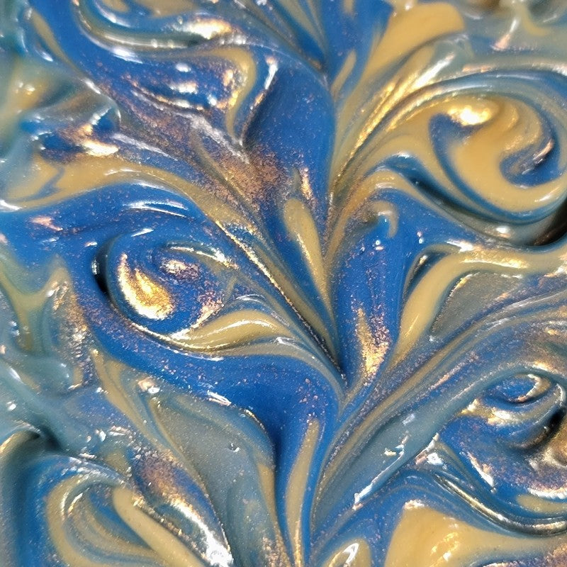 Extreme close-up of freshly poured soap with gold and blue swirls