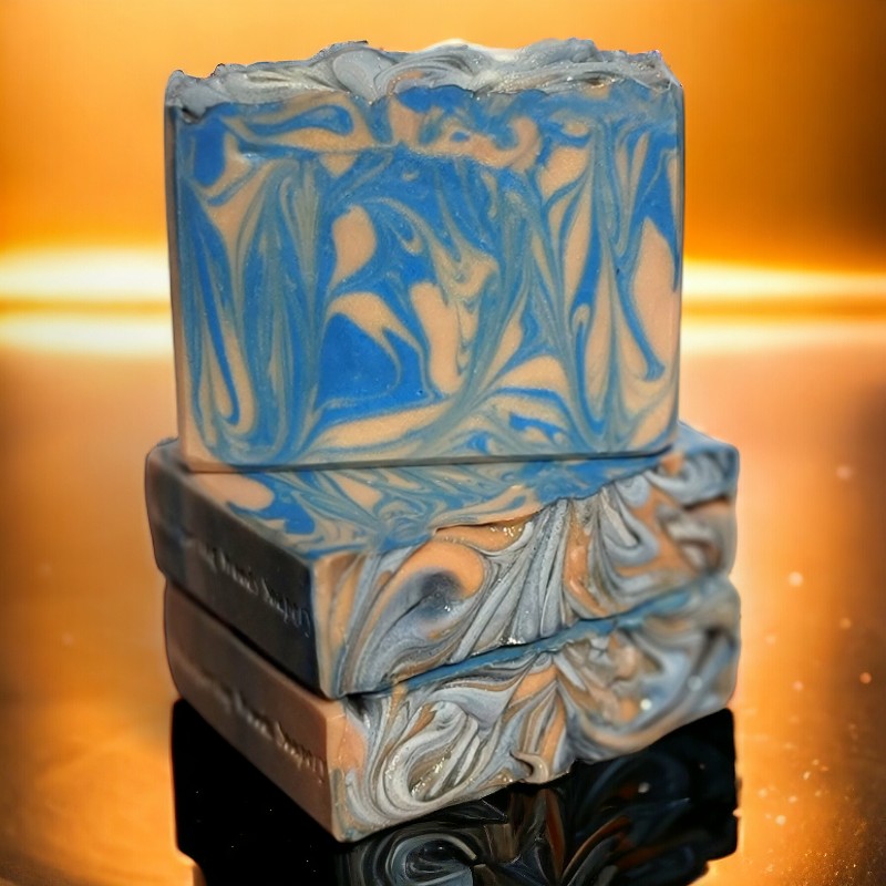 Three bars of gold and blue soap sitting on a reflective orange-gold surface