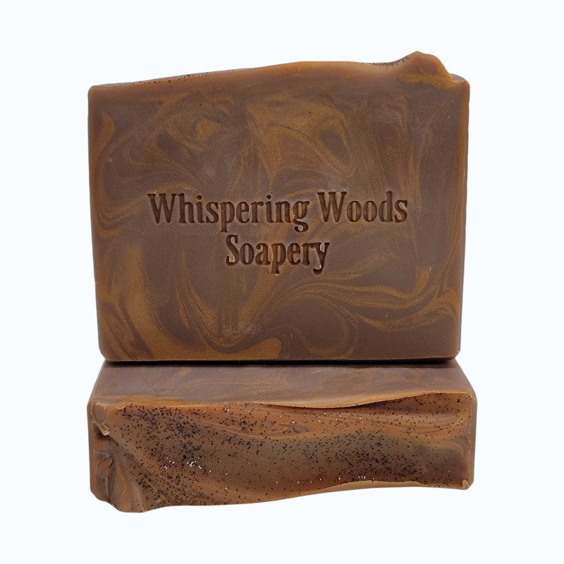 Bar of caramel and brown swirled soap with 'Whispering Woods Soapery' text on a white background