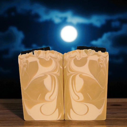 Two bars of orange soap with a marbled pattern against a dark sky with a full moon