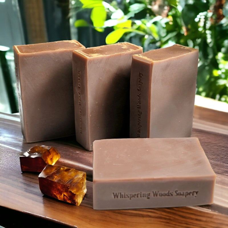 Four brown bars of soap on a wood table, with two blocks of amber beside them