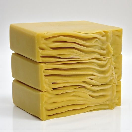 Three stacked golden-yellow soap bars on a white background