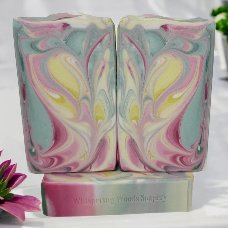 Three bars of light green, white, yellow, and pink swirled soap bars on a white background