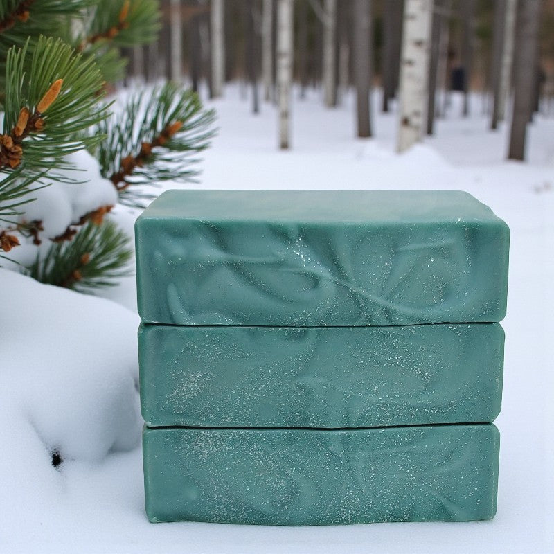 Three stacked green soap bars on a snowy background