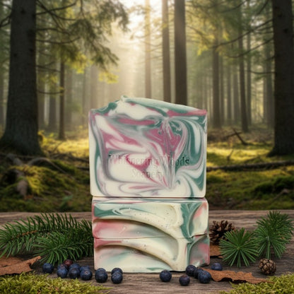 Stack of soap bars with colors of pink and green and white with a forest background