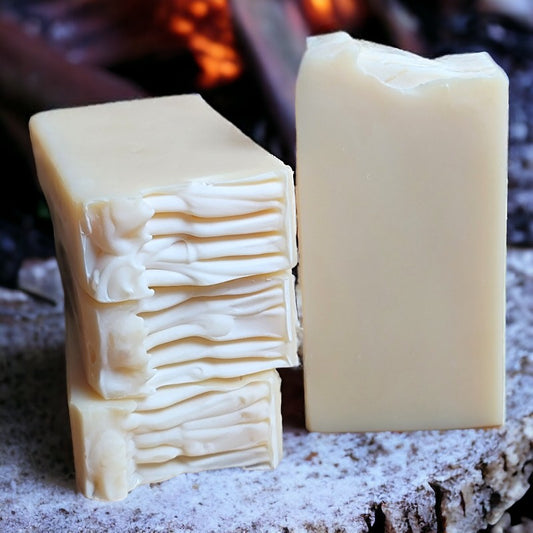 Four bars of cream-colored soap on a stump by a bonfire