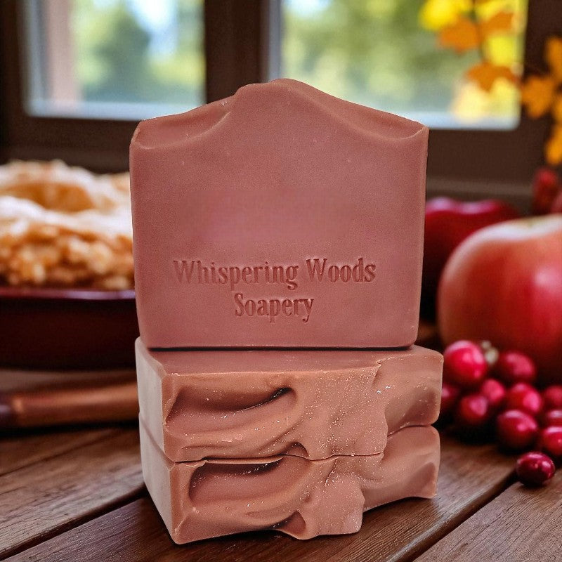 Three berry pink soap bars from Whispering Woods Soapery on a wooden surface with autumn decorations in the background