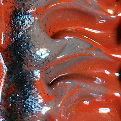 Extreme close-up of freshly poured gray and red swirled soap with biodegradable black glitter down the side