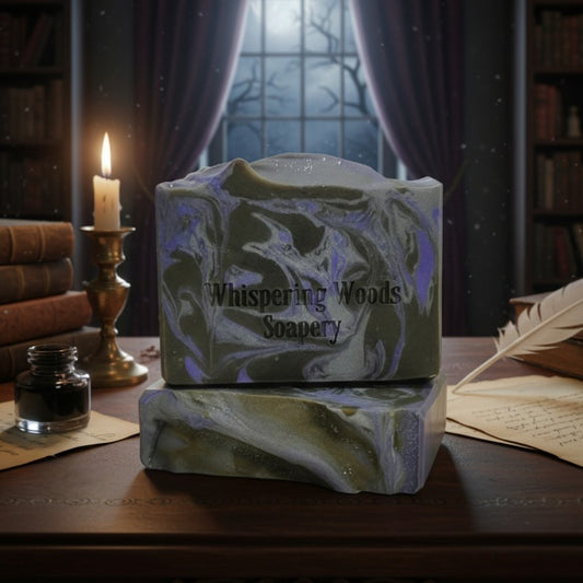Bars of soap with 'Whispering Woods Soapery' branding on a wooden surface with a candle and books in the background