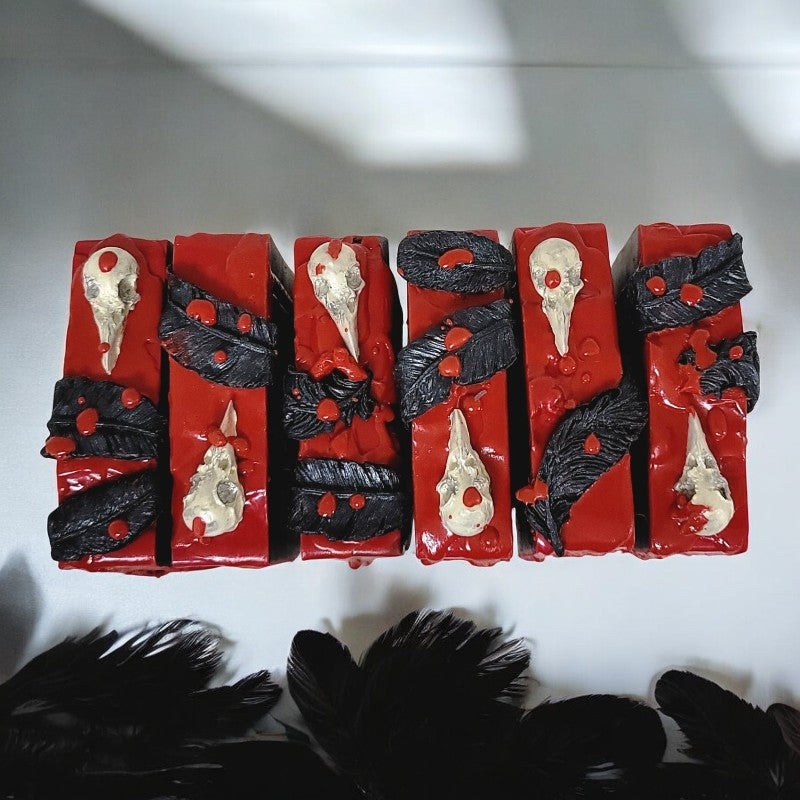 The blood-red tops of six soaps covered in raven skulls and black feathers