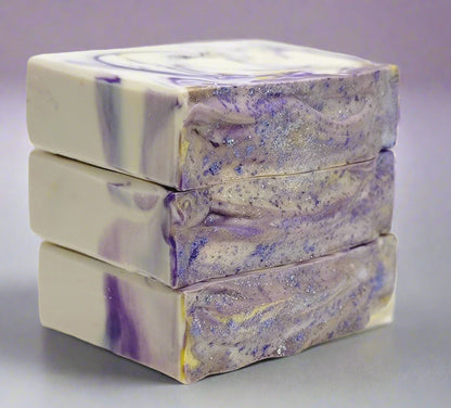 Three bars of soap with a purple and white swirled pattern on a light purple background