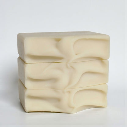 Cream-colored bars of soap stacked on a white surface