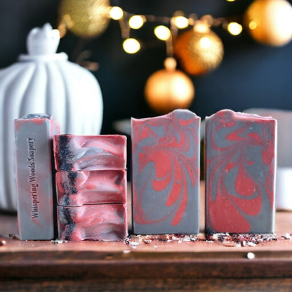 Six bars of gray and red soap on a wood table with blurred gold ornaments in the background