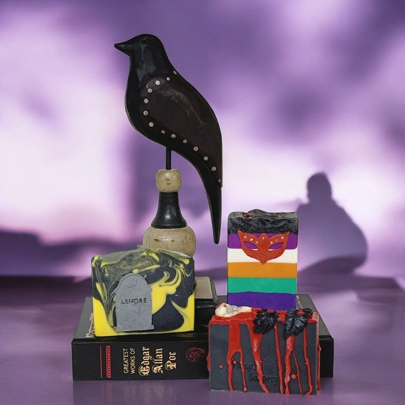 Three Poe collection soaps with an Edgar Allan Poe book and wooden raven figurine