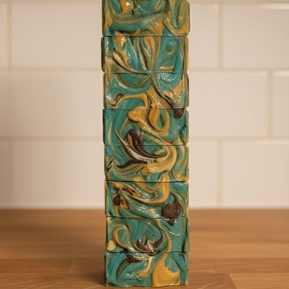 Stack of soaps with textured tops on a wooden counter with white tile in the background