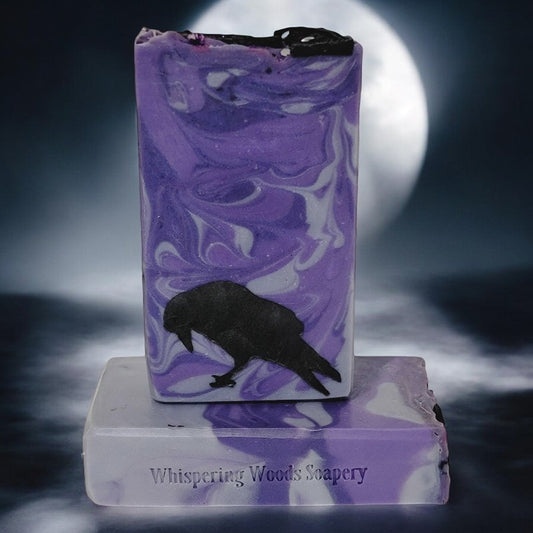 A bar of purple and silver swirled soap with a black raven toward the bottom edge sits in front of a full moon