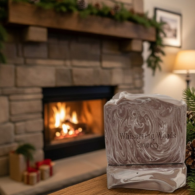 Brown and cream swirled soap bar with 'Whispering Woods Soapery' branding in front of a fireplace