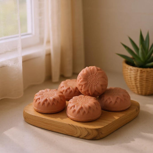 Rose clay flower-shaped facial bars on a wooden board with a plant in the background