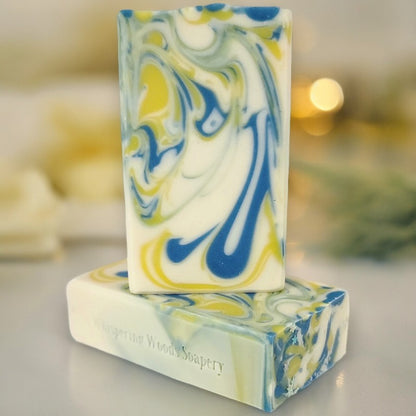 Two bars of white soap with yellow and blue swirls with pale yellow blurry lighting in the background