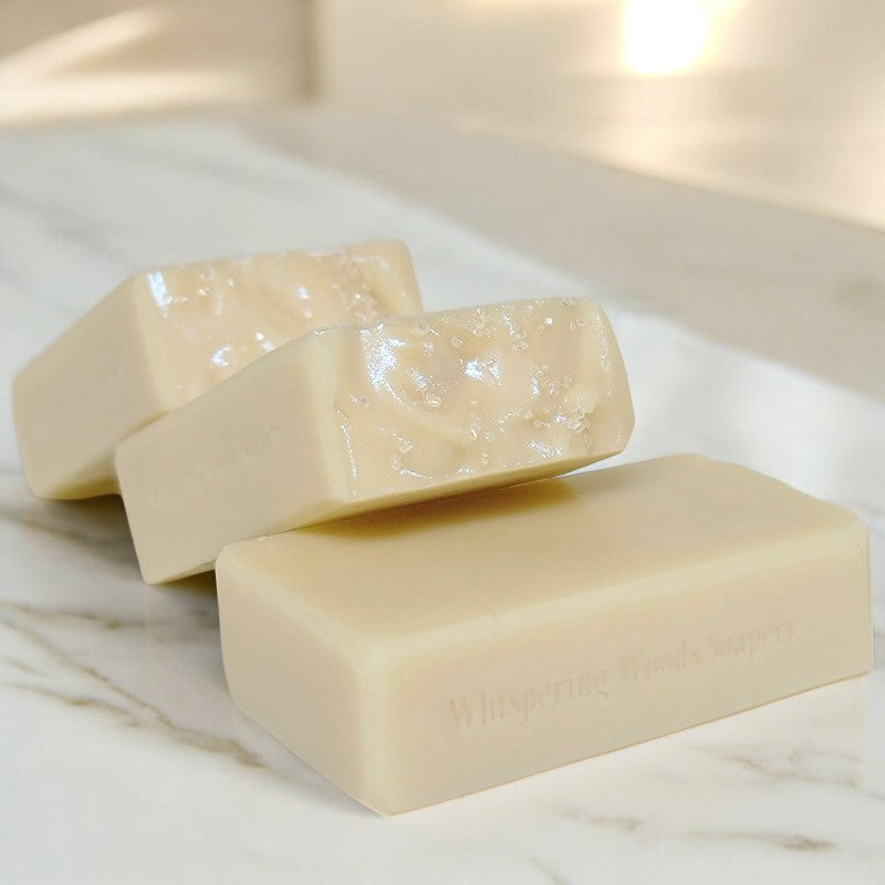 Three cream-colored soap bars lay on a marble counter