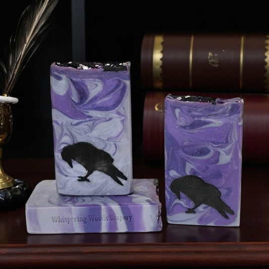 Three purple and silver swirled soap bars with a black silhouette of a raven, set on a writing desk
