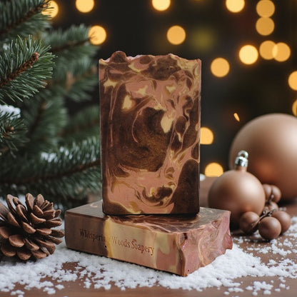 Marbled soap bar in colors of brown, cream and light pink on a wood table with Christmas decorations in the background