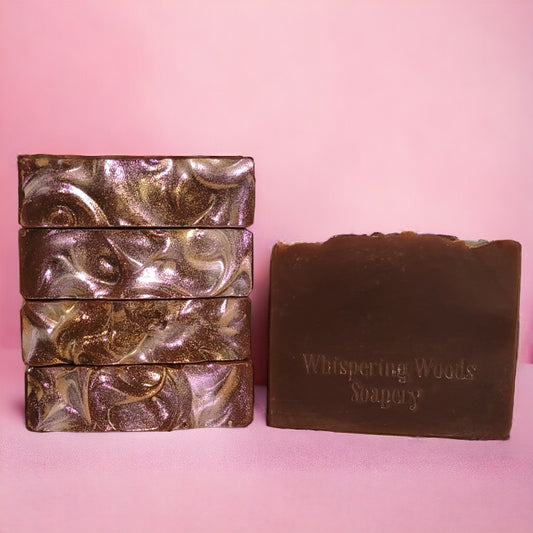 Five dark brown bars of soap with red and gold sparkle on top with a pink background 