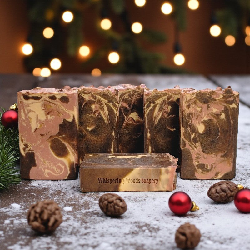Marbled soap bars with 'Whispering Woods Soapery' branding on a wooden surface with Christmas decorations