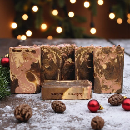 Marbled soap bars with 'Whispering Woods Soapery' branding on a wooden surface with Christmas decorations