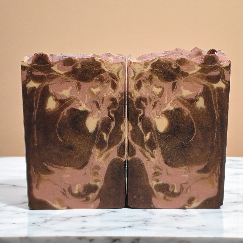 Marbled brown cream and pink soap bar on a countertop with a beige background