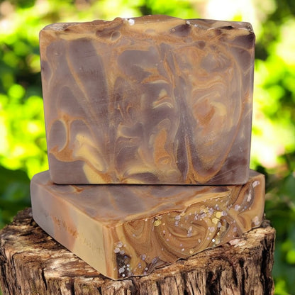 Two brown, gold and copper soap bars on a stump in a sun-dappled woods