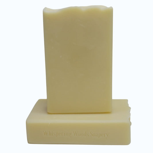Two bars of light yellow soap with 'Whispering Woods Soapery' branding on a white background