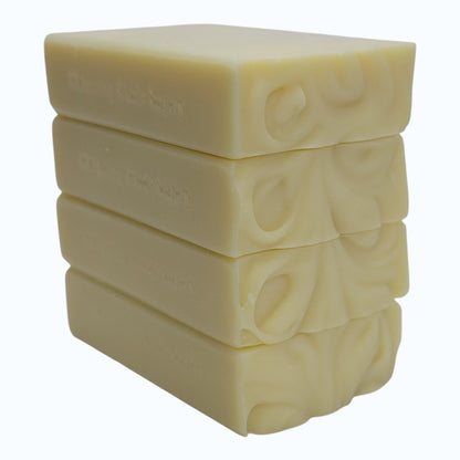 Stack of four rectangular light yellow soap bars on a white background