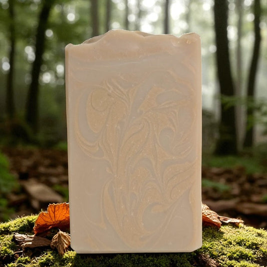 Beautiful tan bar of soap with coppery-gold swirls with a forest in the background