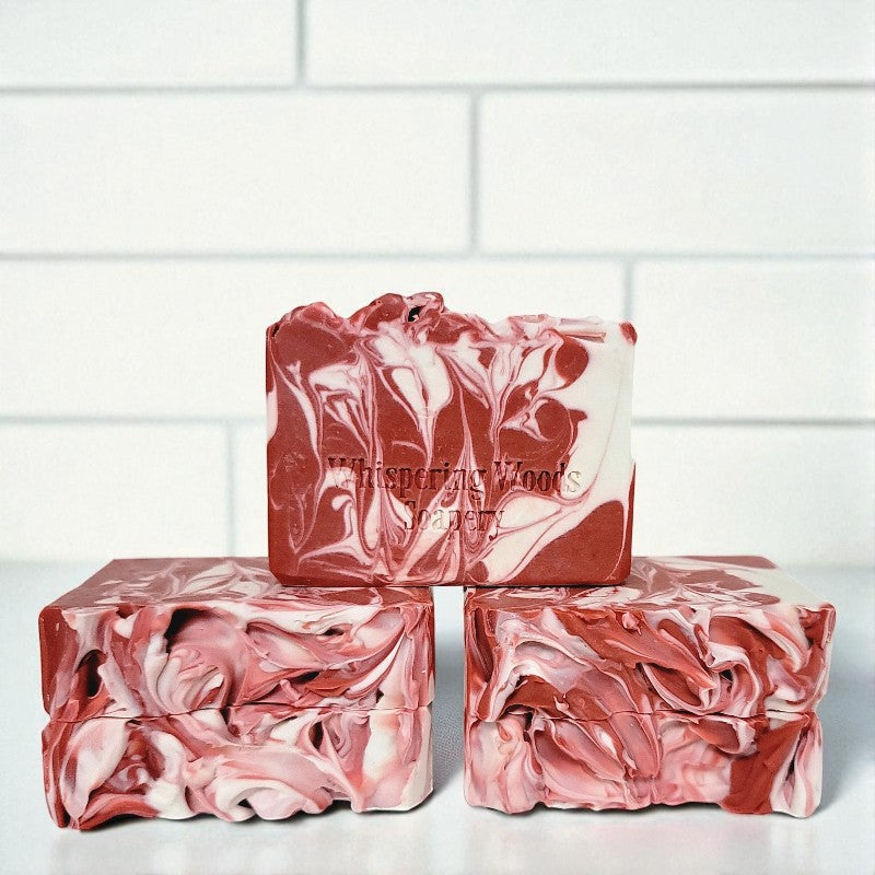 Five bars of marbled pink and white soap on a white surface with a white tiled background
